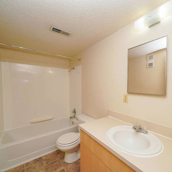 Thumbnail 7 of 8 A bathroom with a toilet, sink, and shower at Madeira Apartments, Michigan