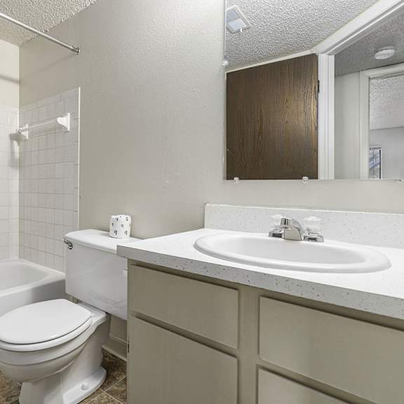 Thumbnail 5 of 8 A white toilet sits next to a white sink in a bathroom at Madeira Apartments, Michigan