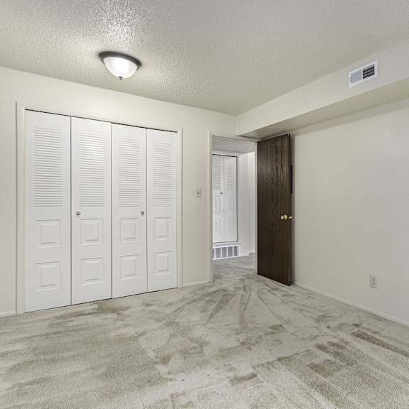 Thumbnail 8 of 8 A bedroom with a large closet and carpeted floor at Madeira Apartments, Michigan