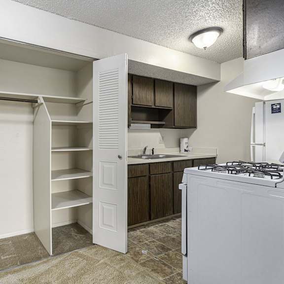 Thumbnail 4 of 8 A large closet and kitchen with white appliances at Madeira Apartments, Michigan