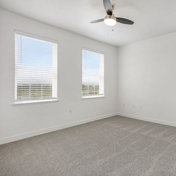 Thumbnail 11 of 11 an empty living room with three windows and a ceiling fan at Meadowbrooke Apartment Homes, Michigan