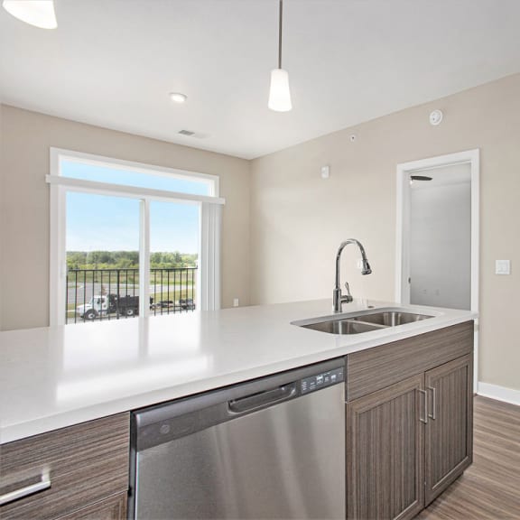 Thumbnail 6 of 11 a kitchen with a sink and a door to a hallway at Meadowbrooke Apartment Homes, Grand Rapids