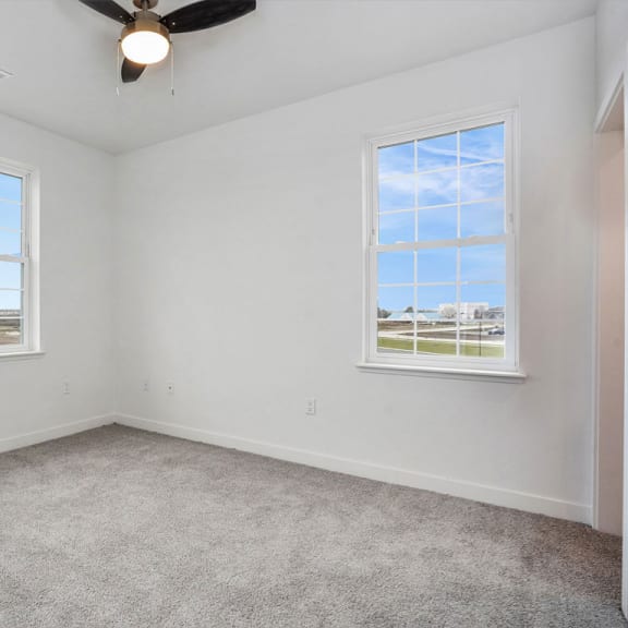 Thumbnail 8 of 9 an empty room with two windows and a ceiling fan at Meadowbrooke Apartment Homes, Michigan