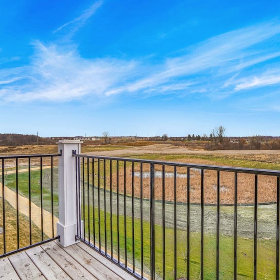 Thumbnail 4 of 9 a view of a field from a balcony with a blue sky at Meadowbrooke Apartment Homes, Grand Rapids