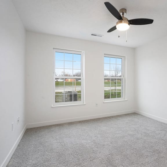 Thumbnail 8 of 9 an empty living room with a ceiling fan and two windows at Meadowbrooke Apartment Homes, Grand Rapids, MI, 49512