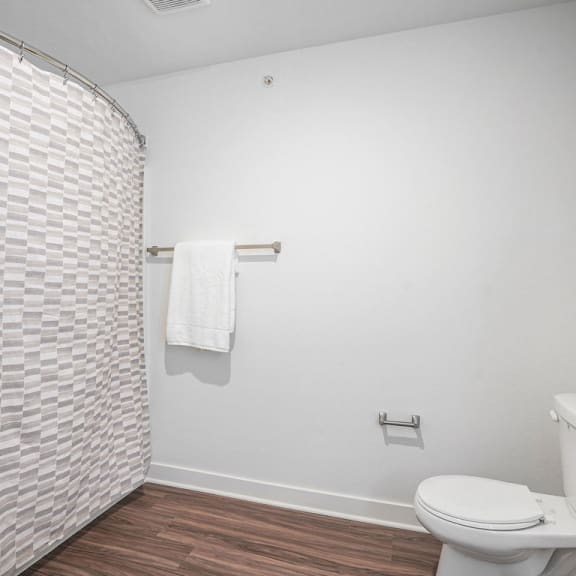 Thumbnail 6 of 10 a white bathroom with a toilet and a shower at Meadowbrooke Apartment Homes, Michigan