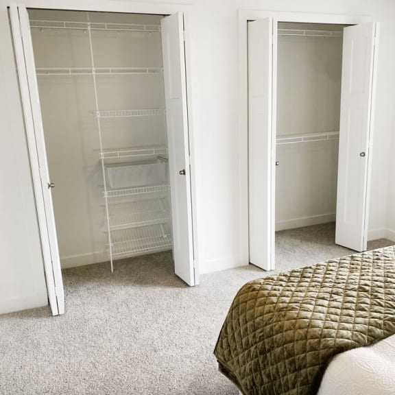 Thumbnail 9 of 10 a bedroom with closet doors and a bed at Meadowbrooke Apartment Homes, Grand Rapids, Michigan