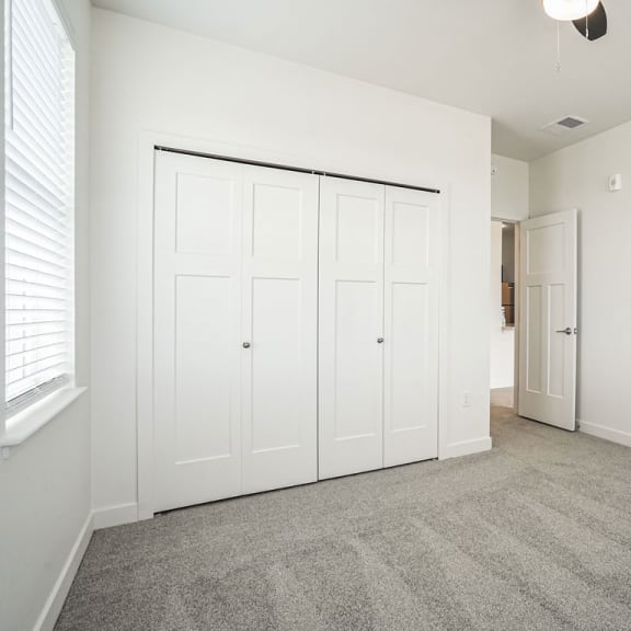 Thumbnail 9 of 12 a bedroom with white walls and carpet and a door to a closet at Meadowbrooke Apartment Homes, Grand Rapids, MI