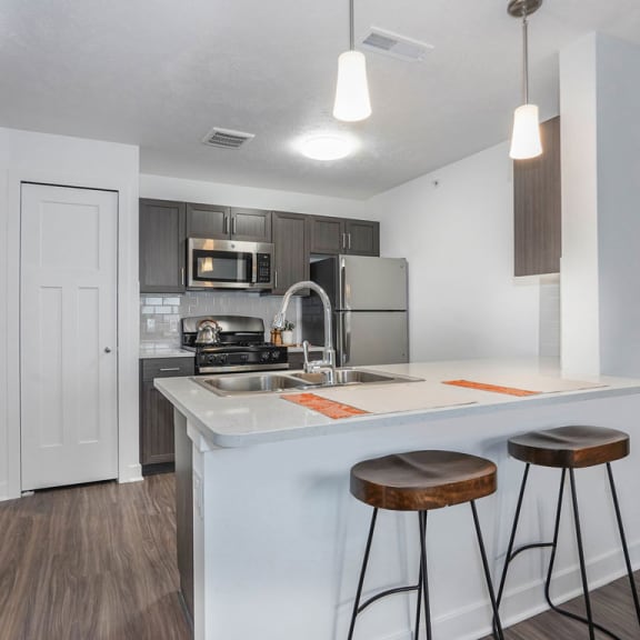 Thumbnail 6 of 9 a kitchen with a counter top with two stools at Meadowbrooke Apartment Homes, Grand Rapids, MI
