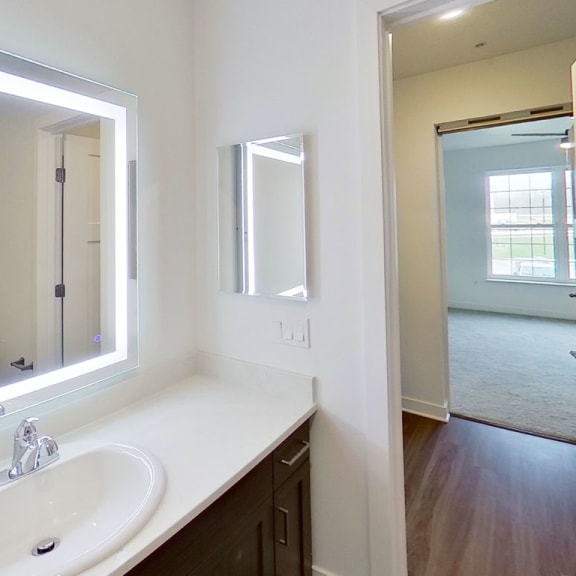 Thumbnail 8 of 10 a bathroom with a sink and a large mirror at Meadowbrooke Apartment Homes, Michigan