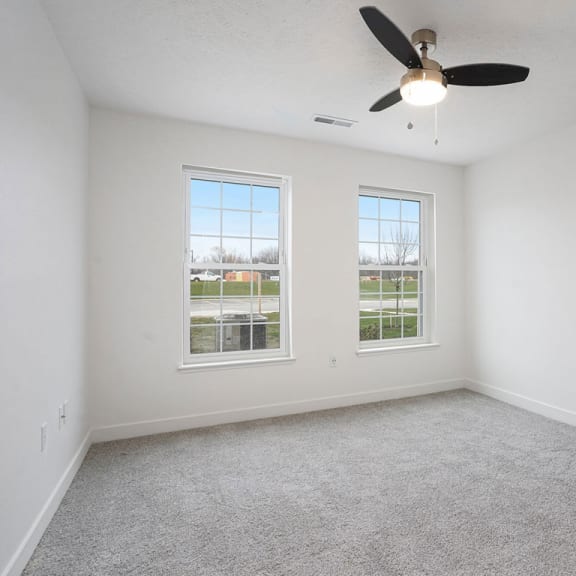 Thumbnail 9 of 10 an empty living room with a ceiling fan and two windows at Meadowbrooke Apartment Homes, Michigan