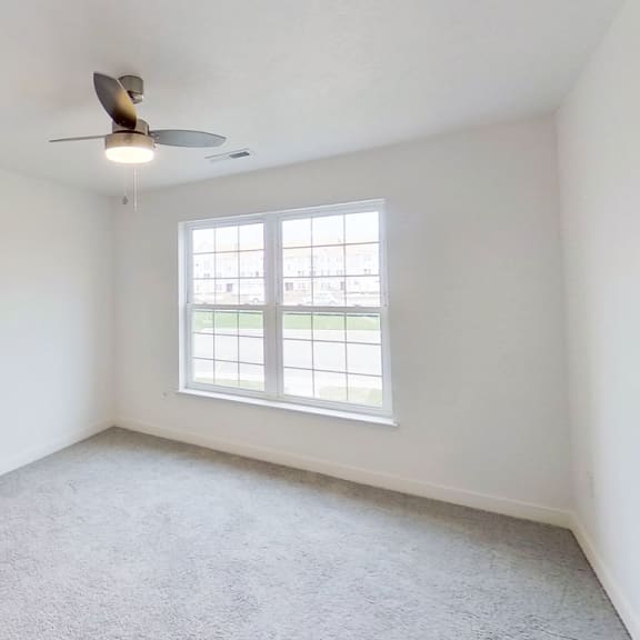 Thumbnail 7 of 10 an empty living room with a window and a ceiling fan at Meadowbrooke Apartment Homes, Michigan