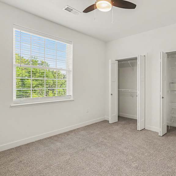 Thumbnail 15 of 15 A bedroom with a ceiling fan and a window with blinds at Meadowbrooke Apartment Homes in Grand Rapids, MI 49512