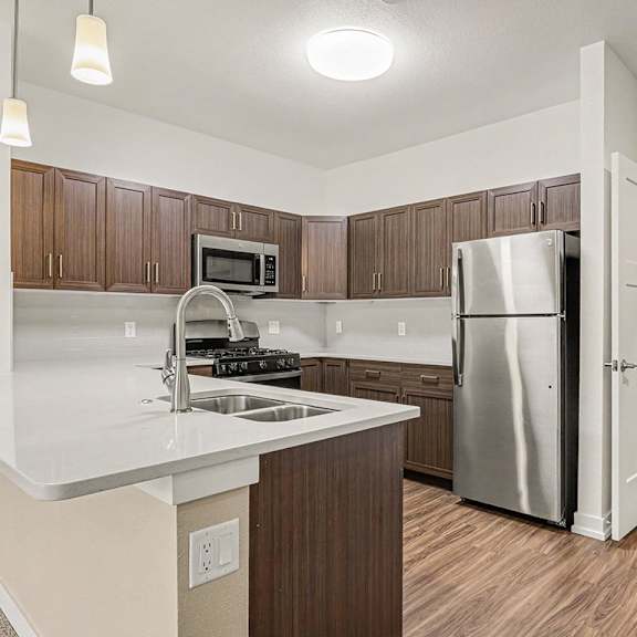 Thumbnail 10 of 15 A kitchen with hard-surface counter tops and a stainless steel refrigerator at Meadowbrooke Apartment Homes in Grand Rapids, MI 49512