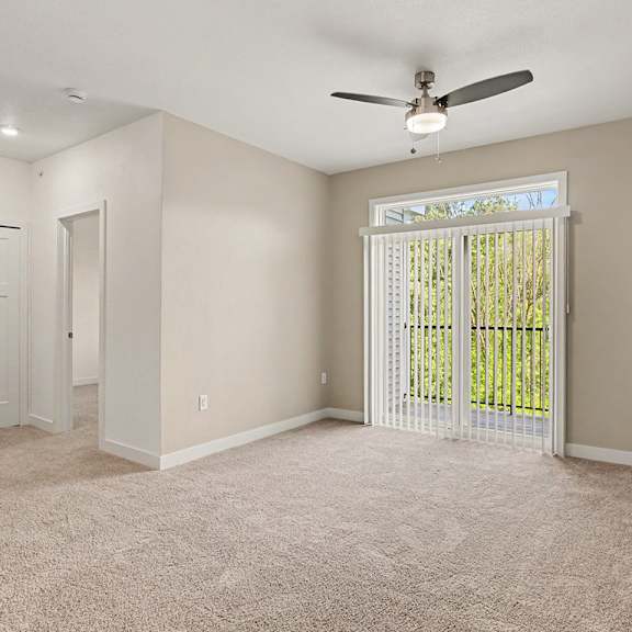 Thumbnail 6 of 15 A living room with a ceiling fan and carpeted floor at Meadowbrooke Apartment Homes in Grand Rapids, MI 49512
