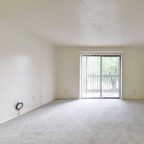 Thumbnail 3 of 11 an empty living room with a sliding glass door to a balcony at Old Monterey Apartments, Missouri, 65807