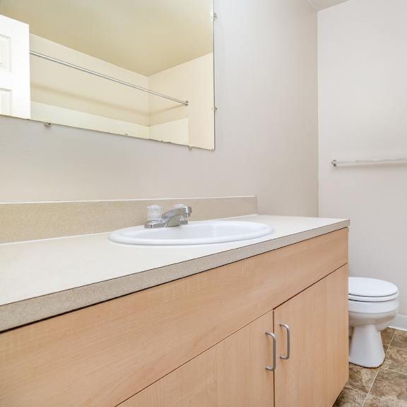 Thumbnail 10 of 14 A bathroom with a toilet, sink, and a mirror at Mount Royal Townhomes in Kalamazoo, MI