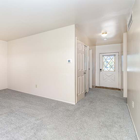 Thumbnail 3 of 14 An entryway and living room with a carpeted floor at Mount Royal Townhomes in Kalamazoo, MI