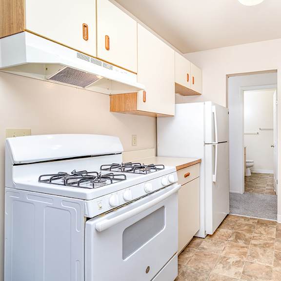 Thumbnail 8 of 14 A kitchen with a white stove and cabinets at Mount Royal Townhomes in Kalamazoo, MI