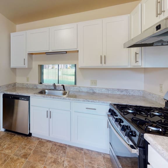 Thumbnail 4 of 7 a kitchen with white cabinets and a stove and a sink at Mount Royal Townhomes, Kalamazoo