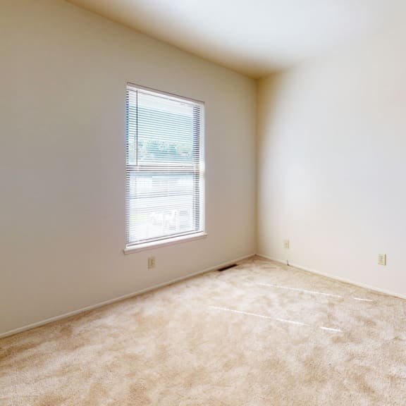 Thumbnail 12 of 13 an empty bedroom with a window and carpeting at Mount Royal Townhomes, Kalamazoo, MI