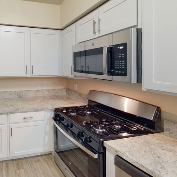 Thumbnail 4 of 7 a kitchen with white cabinets and a stove and a microwave at North Pointe Apartments in Elkhart, IN