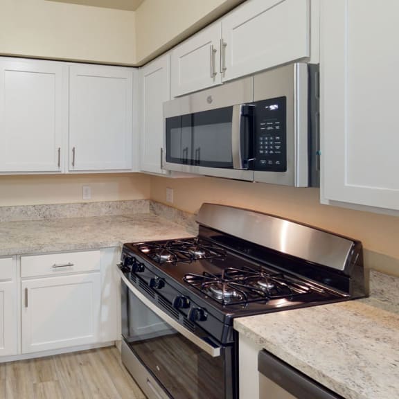Thumbnail 9 of 14 a kitchen with white cabinets and a stove and a microwave at North Pointe Apartments, Elkhart, IN