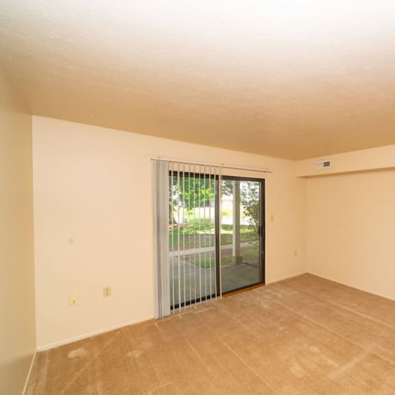 Thumbnail 7 of 14 an empty living room with a sliding glass door to a patio at North Pointe Apartments, Elkhart, IN