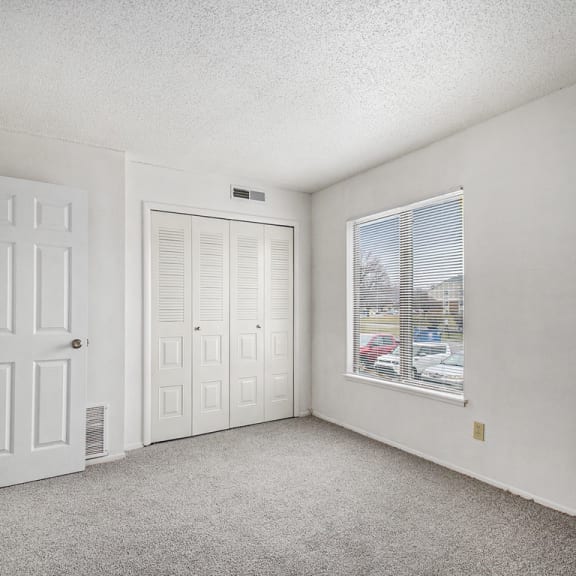 Thumbnail 18 of 19 an empty bedroom with a window and a door at Normandy Village Apartments, Michigan City, Indiana