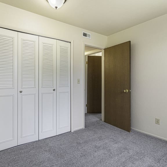 Thumbnail 16 of 19 a bedroom with closet doors and a door to a hallway at Normandy Village Apartments, Michigan City