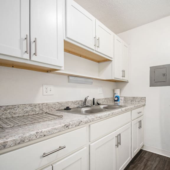 Thumbnail 12 of 19 a renovated kitchen with white cabinets and a sink and a refrigerator at Normandy Village Apartments, Indiana
