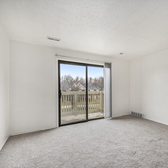 Thumbnail 5 of 19 an empty living room with a sliding glass door to a balcony at Normandy Village Apartments, Michigan City, IN, 46360
