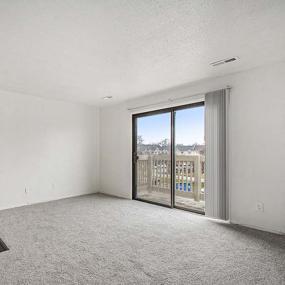 Thumbnail 4 of 19 A living room with plush carpet, and a slider to a balcony with a view at Normandy Village Apartments, Michigan City, 46360
