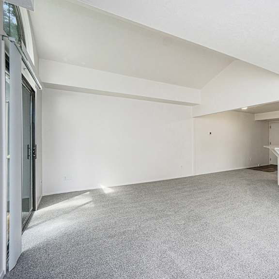 Thumbnail 3 of 10 A large, empty living room with white walls and a grey carpet at North Pointe Apartments, Elkhart, IN, 46514