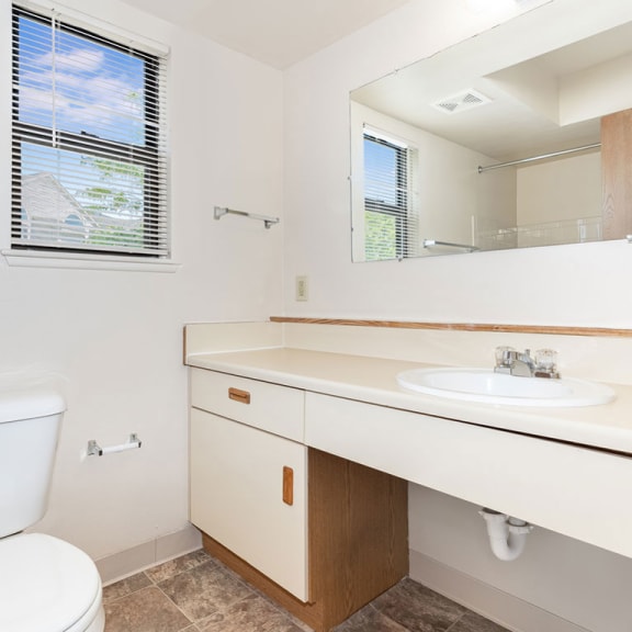 Thumbnail 8 of 11 a bathroom with a toilet sink and a mirror  at Oak Shores Apartments, Oak Creek, WI, 53154