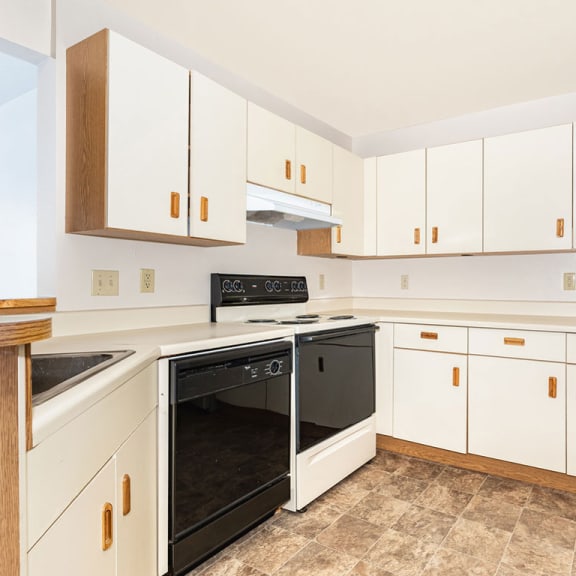 Thumbnail 6 of 9 a kitchen with white cabinets and a black stove and oven  at Oak Shores Apartments, Wisconsin, 53154