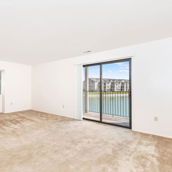 Thumbnail 3 of 11 an empty living room with a sliding glass door to a balcony  at Oak Shores Apartments, Oak Creek, WI