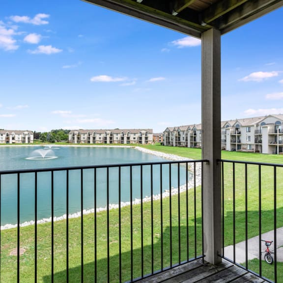 Thumbnail 5 of 9 a balcony with a view of a lake and some apartment buildings  at Oak Shores Apartments, Oak Creek, WI