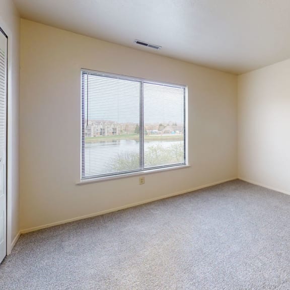 Thumbnail 8 of 9 an empty room with a window and carpeting  at Oak Shores Apartments, Oak Creek, Wisconsin