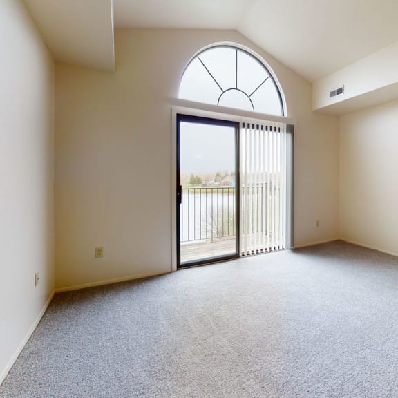 Thumbnail 4 of 9 an empty living room with a glass door to a balcony  at Oak Shores Apartments, Oak Creek