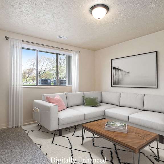 Thumbnail 3 of 13 A garden style living room with a white couch, a coffee table, and a large window at Old Farm Apartments, Elkhart, 46517