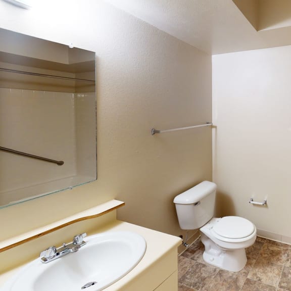 Thumbnail 7 of 12 a bathroom with a toilet and a sink and a mirror at Orchard Lakes Apartments, Toledo, Ohio