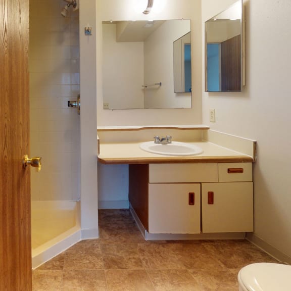 Thumbnail 7 of 8 a bathroom with a toilet sink and a mirror at Pine Knoll Apartments, Battle Creek, MI, 49014