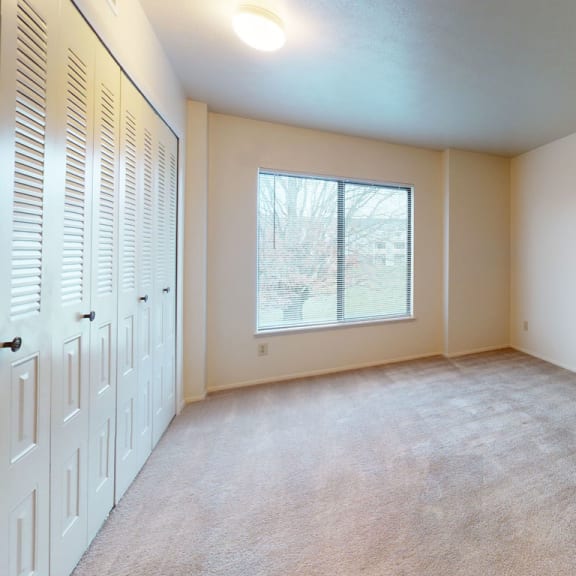 Thumbnail 6 of 8 an empty living room with a window and a closet at Pine Knoll Apartments, Battle Creek, MI