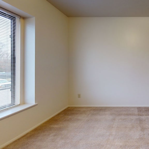 Thumbnail 8 of 8 a empty room with a large window and carpet  at Pine Knoll Apartments, Battle Creek, MI