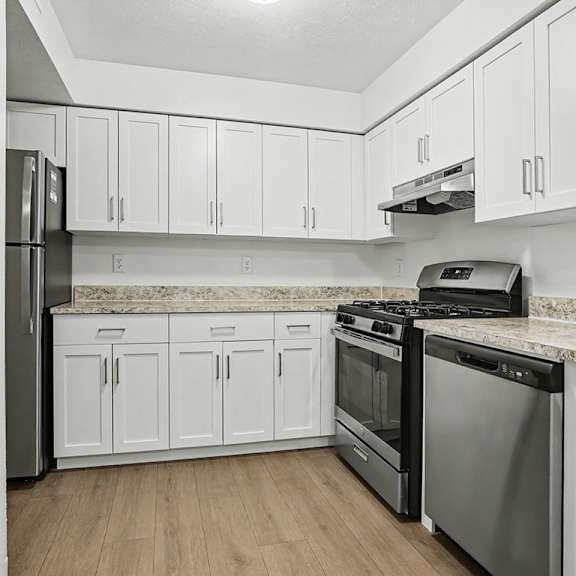 Thumbnail 9 of 17 A kitchen with white cabinets and stainless steel appliances at Pine Knoll Apartments, Battle Creek