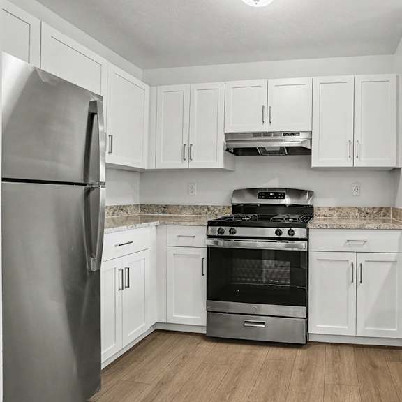 Thumbnail 6 of 16 A kitchen with white cabinets and a stainless steel refrigerator at Pine Knoll Apartments, Battle Creek