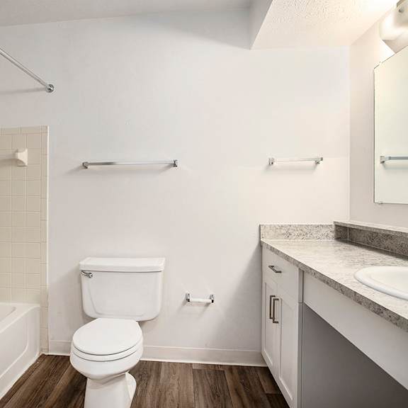 Thumbnail 9 of 17 A white bathroom with a toilet, sink, and bathtub at Pine Knoll Apartments, Battle Creek, 49014
