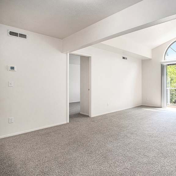 Thumbnail 3 of 17 A living room with a cathedral ceiling, large window and carpeted floor at Pine Knoll Apartments, Battle Creek, 49014