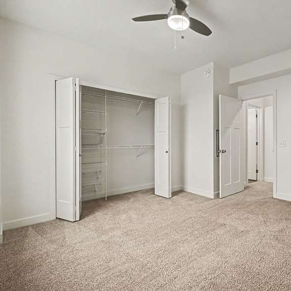 Thumbnail 12 of 12 A bedroom with a walk-in closet and ceiling fan at The Reserve at The Reserve at Destination Pointe in Grimes, IA 50111